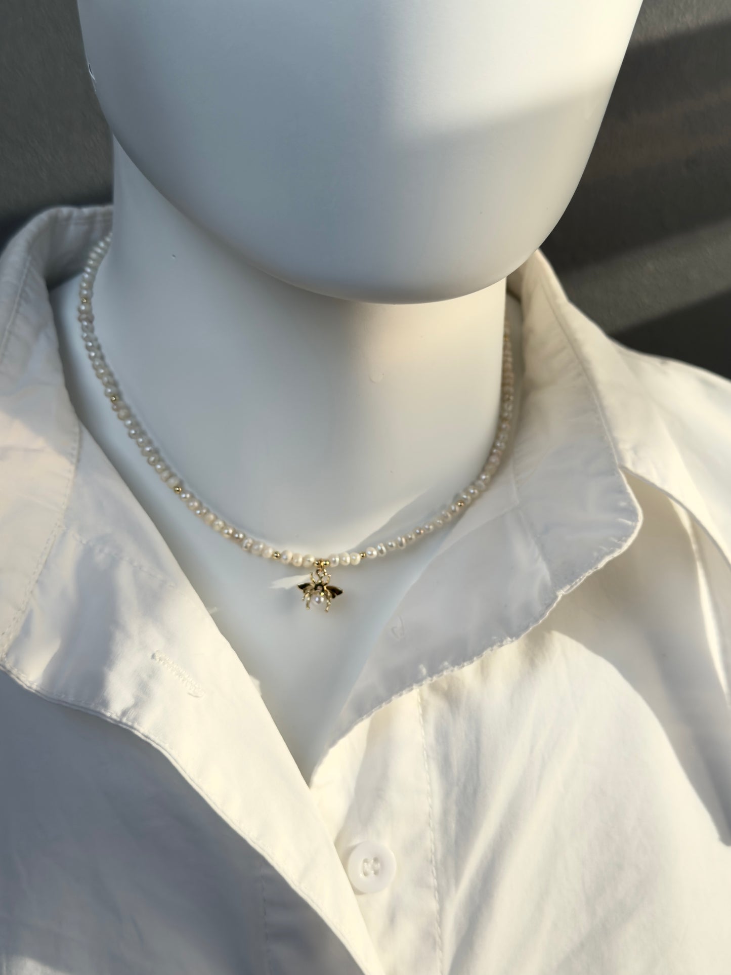 Collier de perles blanches avec pendentif abeille