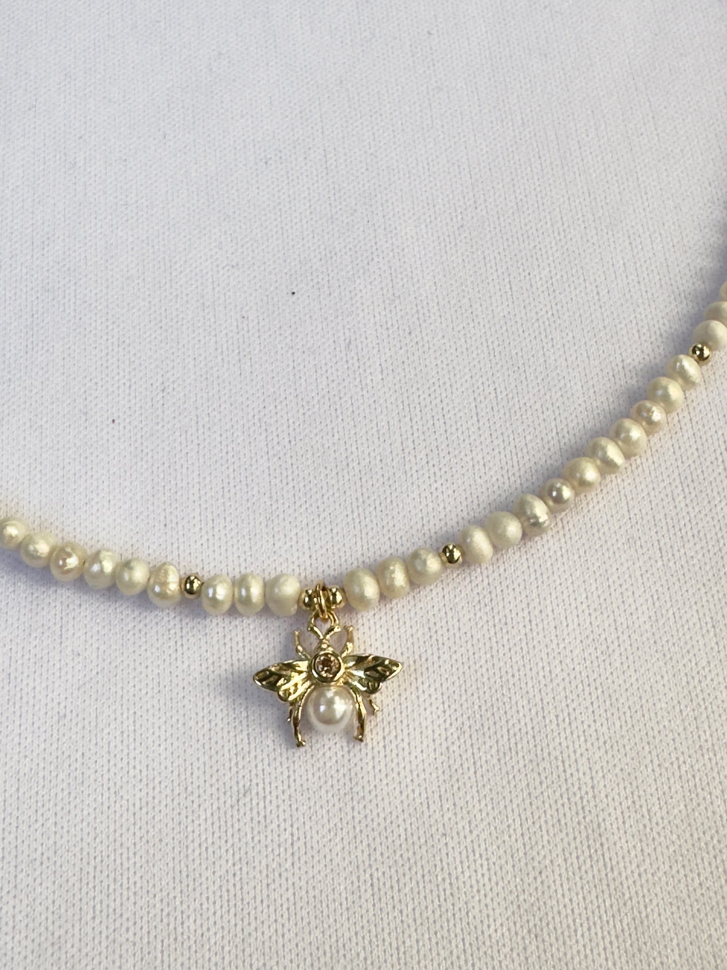 Collier de perles blanches avec pendentif abeille